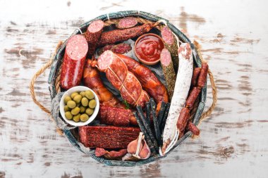 Sosis ve aperatifler mezarda ürün yelpazesine. Sosis Fuet, salam, paperoni. Beyaz ahşap zemin üzerinde. Üstten görünüm. Metniniz için boş alan.