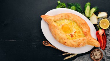 Khachapuri yumurta ve peynir ile. Gürcü mutfağı. Eski ahşap arka plan üzerinde. Metin için özgür yer. Üstten görünüm.