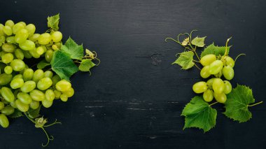 Taze yeşil üzüm üzüm yaprakları ile. Üstten görünüm. Siyah ahşap arka plan üzerinde. Metin için boş alan.
