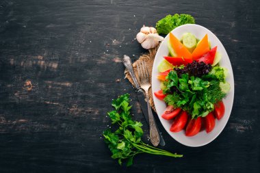 Dilimlenmiş taze sebze bir tabak. Salata. Eski ahşap arka plan üzerinde. Metin için özgür yer. Üstten görünüm.