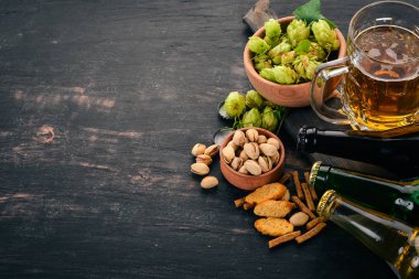 Bira ve aperatifler bir seçim. Light bira, karanlık bira, canlı bira. Siyah ahşap arka plan üzerinde. Metin için özgür yer. Üstten görünüm.