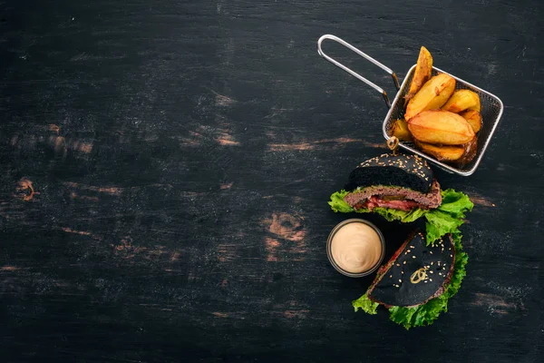 Baked potatoes and Burger with meat, tomatoes and onions. On a wooden background. Free space for text. Top view.