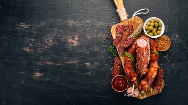 Sosis Fuet, salam, karton mutfak gemide. Siyah bir arka plan üzerinde. Üstten görünüm. Metniniz için boş alan.