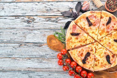 Pizza jambon, füme domates ve mozzarella peyniri. İtalyan mutfağı. Ahşap bir arka plan üzerinde. Metin için özgür yer. Üstten görünüm.