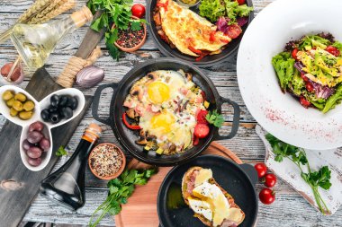 Bir dizi yemek. Shakshuka, omlet, avokado salata, haşlanmış yumurta ile sandviç. Ahşap bir arka plan üzerinde. Metin için özgür yer. Üstten görünüm.