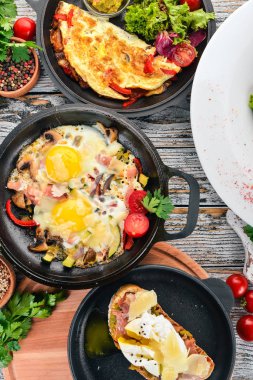 Bir dizi yemek. Shakshuka, omlet, avokado salata, haşlanmış yumurta ile sandviç. Ahşap bir arka plan üzerinde. Metin için özgür yer. Üstten görünüm.