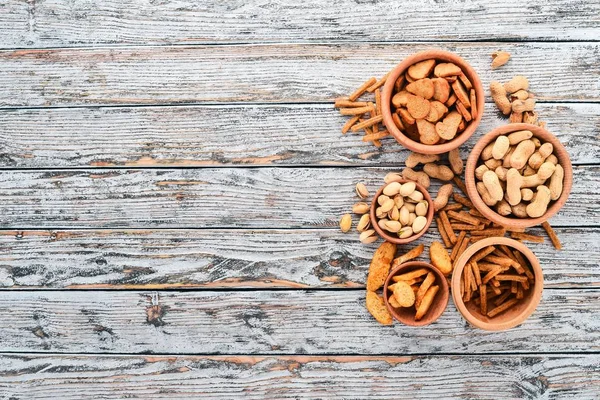 Snack for beer. Salted crackers, chips, nuts, peanuts, pistachios. On a wooden background. Free space for text. Top view.