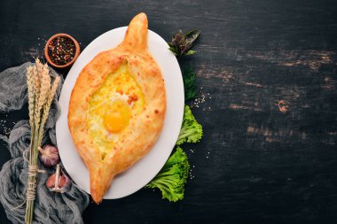 Khachapuri yumurta ve peynir ile. Gürcü mutfağı. Eski ahşap arka plan üzerinde. Metin için özgür yer. Üstten görünüm.