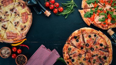 Pizza kümesi. Siyah ahşap arka plan üzerinde. Metin için özgür yer. Üstten görünüm.