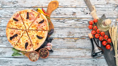 Pizza jambon, füme domates ve mozzarella peyniri. İtalyan mutfağı. Ahşap bir arka plan üzerinde. Metin için özgür yer. Üstten görünüm.