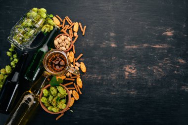 Bira ve aperatifler bir seçim. Light bira, karanlık bira, canlı bira. Siyah ahşap arka plan üzerinde. Metin için özgür yer. Üstten görünüm.