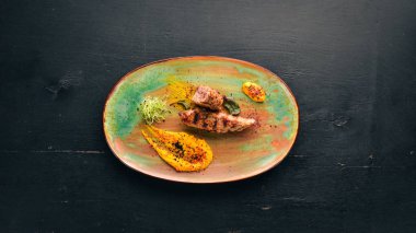 Bir plaka üzerinde soslu pişmiş domuz. Eski arka plan üzerinde. Ücretsiz kopya alanı. Üstten görünüm.