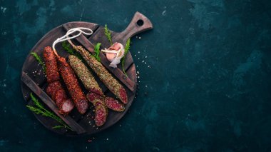 Sosis Fuet, salam, karton mutfak gemide. Siyah bir arka plan üzerinde. Üstten görünüm. Metniniz için boş alan.