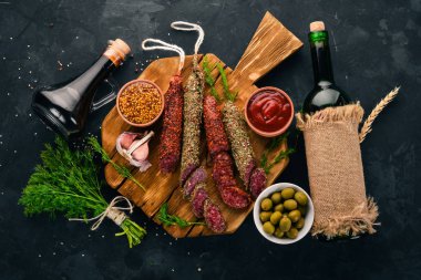 Sosis Fuet, salam, karton mutfak gemide. Siyah bir arka plan üzerinde. Üstten görünüm. Metniniz için boş alan.