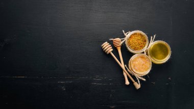 Bal ve arı ürünleri kümesi. Petek tatlım. Siyah ahşap arka plan üzerinde. Metin için özgür yer. Üstten görünüm.