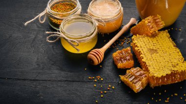 Bal ve arı ürünleri kümesi. Petek tatlım. Siyah ahşap arka plan üzerinde. Metin için özgür yer. Üstten görünüm.