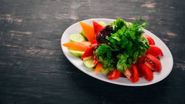 Dilimlenmiş taze sebze bir tabak. Salata. Eski ahşap arka plan üzerinde. Metin için özgür yer. Üstten görünüm.