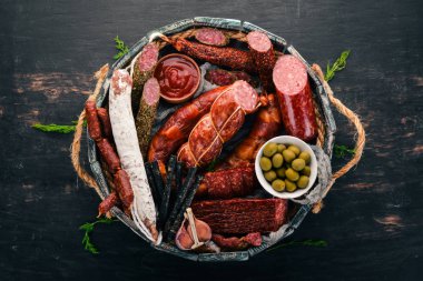 Sosis ve aperatifler mezarda ürün yelpazesine. Sosis Fuet, salam, paperoni. Siyah bir arka plan üzerinde. Üstten görünüm. Metniniz için boş alan.
