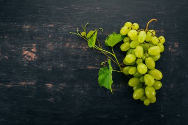 Taze yeşil üzüm üzüm yaprakları ile. Üstten görünüm. Siyah ahşap arka plan üzerinde. Metin için boş alan.