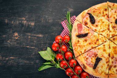 Pizza jambon, füme domates ve mozzarella peyniri. İtalyan mutfağı. Ahşap bir arka plan üzerinde. Metin için özgür yer. Üstten görünüm.