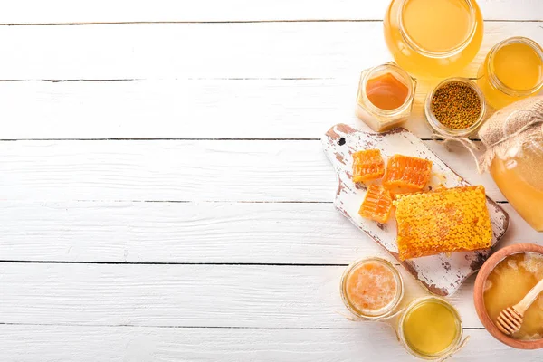 Arı ürünleri ve bal beyaz ahşap zemin üzerinde kümesi. Metin için özgür yer. Üstten görünüm.