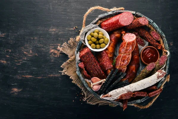 Sosis ve aperatifler mezarda ürün yelpazesine. Sosis Fuet, salam, paperoni. Siyah bir arka plan üzerinde. Üstten görünüm. Metniniz için boş alan.