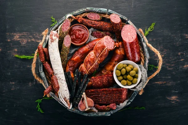 Sosis ve aperatifler mezarda ürün yelpazesine. Sosis Fuet, salam, paperoni. Siyah bir arka plan üzerinde. Üstten görünüm. Metniniz için boş alan.