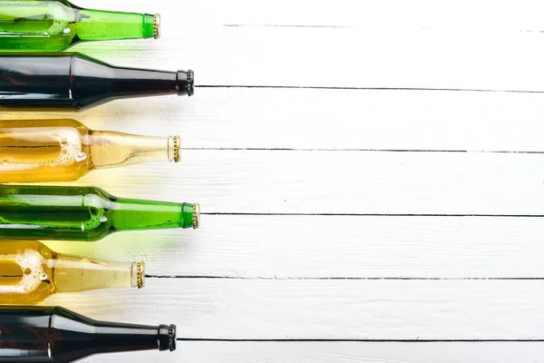 A large selection of beer bottles. On a white wooden table. Free space for text. Top view.