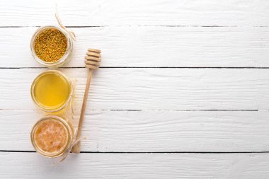 Arı ürünleri ve bal beyaz ahşap zemin üzerinde kümesi. Metin için özgür yer. Üstten görünüm.