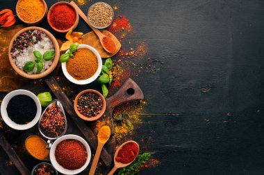 Baharat ve otlar bir ahşap tahta üzerinde. Biber, tuz, kırmızı biber, fesleğen, zerdeçal. Siyah ahşap tahta. Üstten görünüm. Ücretsiz kopya alanı.