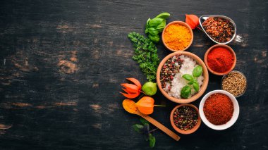 Baharatlar ve otlar kümesi. Hint Mutfak. Biber, tuz, kırmızı biber, fesleğen, zerdeçal. Siyah ahşap tahta. Üstten görünüm. Ücretsiz kopya alanı.