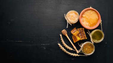 Bal ve arı ürünleri kümesi. Petek tatlım. Siyah ahşap arka plan üzerinde. Metin için özgür yer. Üstten görünüm.