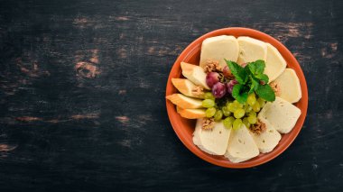 Peynir bir plaka üzerinde. Brynza ve Suluguni peynir. Eski ahşap arka plan üzerinde. Metin için özgür yer. Üstten görünüm.