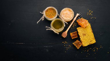 Bal ve arı ürünleri kümesi. Petek tatlım. Siyah ahşap arka plan üzerinde. Metin için özgür yer. Üstten görünüm.