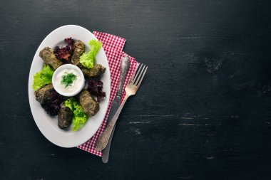 Dolması, dolma, sarma, dolmadakia yaprakları, dolmades beyaz bir tabak. Eski ahşap arka plan üzerinde. Metin için özgür yer. Üstten görünüm.