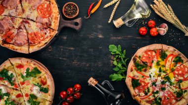 Pizza kümesi. Siyah ahşap arka plan üzerinde. Metin için özgür yer. Üstten görünüm.