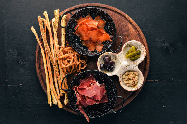 A selection of snacks for beer. Fish, prosciutto, peanuts, olives. On a wooden background. Free copy space. Top view.