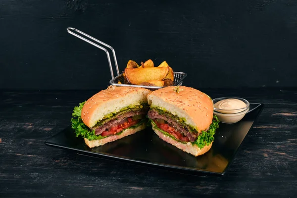 Baked potatoes and Burger with meat, tomatoes and onions. On a wooden background. Free space for text. Top view.