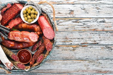 Sosis ve aperatifler mezarda ürün yelpazesine. Sosis Fuet, salam, paperoni. Beyaz ahşap zemin üzerinde. Üstten görünüm. Metniniz için boş alan.