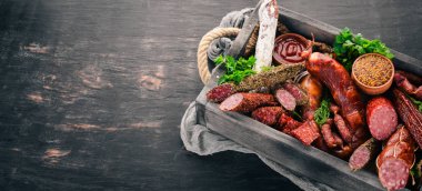 Sosis ve aperatifler mezarda ürün yelpazesine. Sosis Fuet, salam, paperoni. Siyah bir arka plan üzerinde. Üstten görünüm. Metniniz için boş alan.