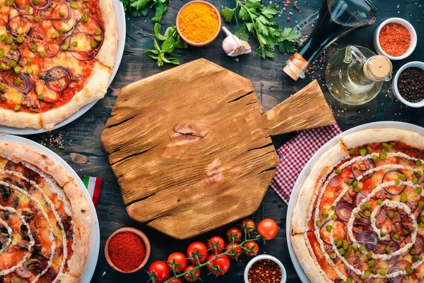 A set of Italian pizza. Italian cuisine. On a black wooden background. Free copy space. Top view.