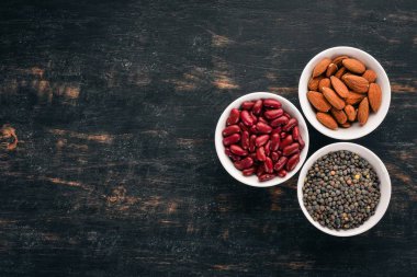 Mercimek, badem ve fasulye. Siyah ahşap arka plan üzerinde. Üstten görünüm. Ücretsiz kopya alanı.