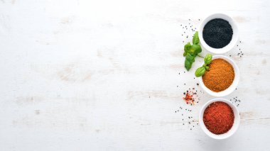 Baharat ve otlar Beyaz ahşap bir masa üzerinde bir dizi. Fesleğen, karabiber, safran, baharatlar. Hint geleneksel mutfak. Üstten görünüm. Ücretsiz kopya alanı.