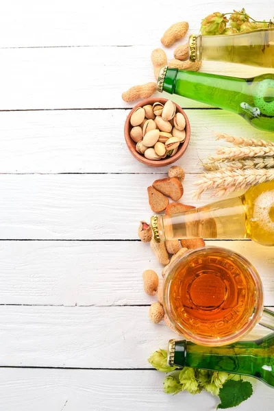 Background beer and snacks. Hops, beer, chips, nuts. On a white wooden background. Free space for text. Top view.