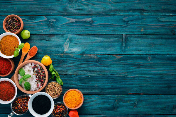 Spices and herbs on a blue wooden table. Basil, pepper, saffron, spices. Indian traditional cuisine. Top view. Free copy space.