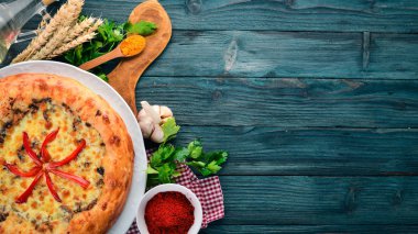 Khachapuri peynir, mantar ve kırmızı biber. Eski ahşap arka plan üzerinde. Metin için özgür yer. Üstten görünüm.