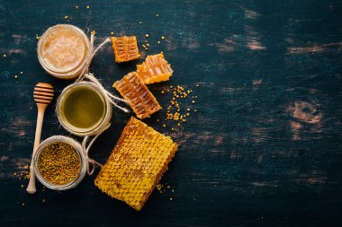 Bal ve arı ürünleri kümesi. Petek tatlım. Siyah ahşap arka plan üzerinde. Metin için özgür yer. Üstten görünüm.