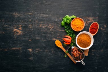 Baharatlar ve otlar kümesi. Hint Mutfak. Biber, tuz, kırmızı biber, fesleğen, zerdeçal. Siyah ahşap tahta. Üstten görünüm. Ücretsiz kopya alanı.