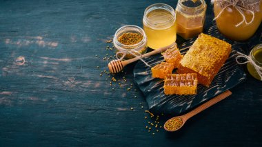 Bal ve arı ürünleri kümesi. Petek tatlım. Siyah ahşap arka plan üzerinde. Metin için özgür yer. Üstten görünüm.