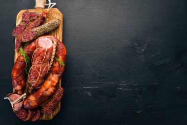 Sosis Fuet, salam, karton mutfak gemide. Siyah bir arka plan üzerinde. Üstten görünüm. Metniniz için boş alan.